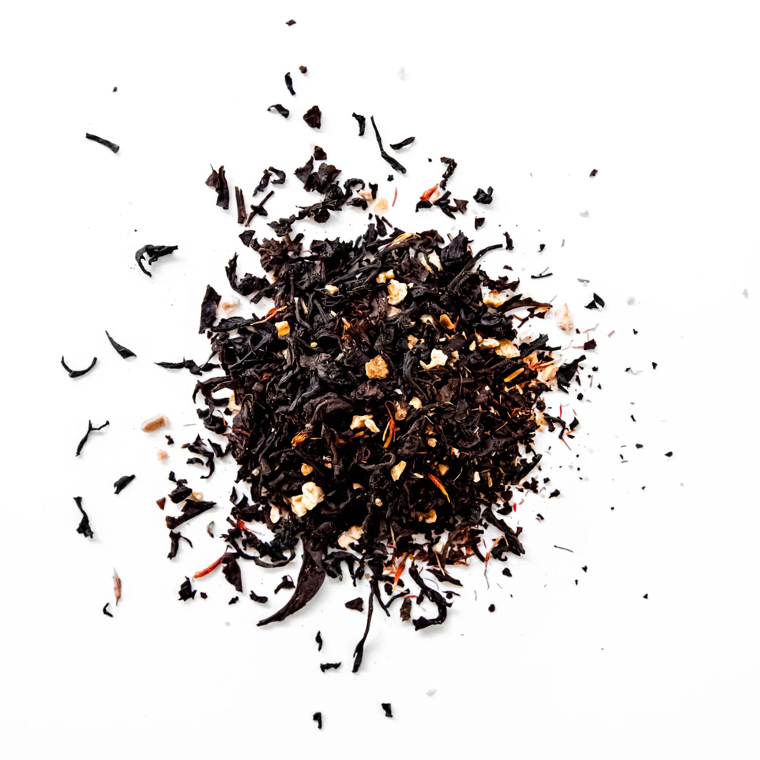 Loose leaf Mango Ceylon black tea with dried mango pieces scattered on white background, by Yerba Buena Tea Company.
